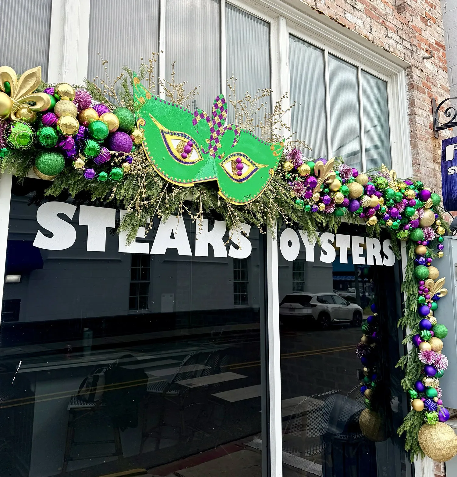 Hand-painted Mardi Gras mask and garland on a storefront