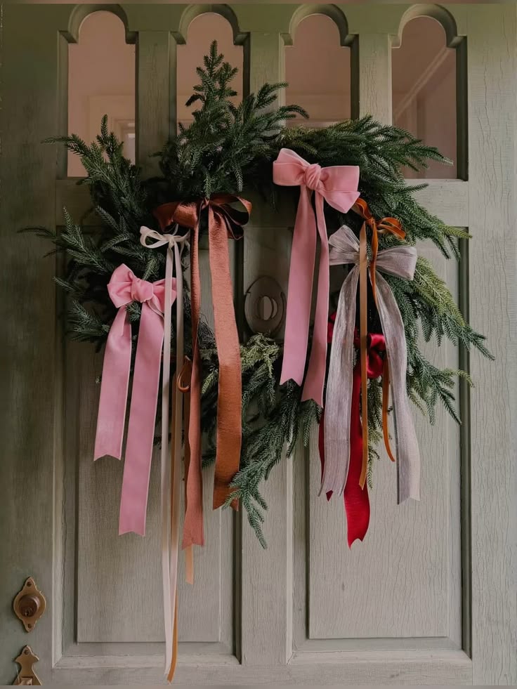 Evergreen wreath layered with pink, rust and red ribbons
